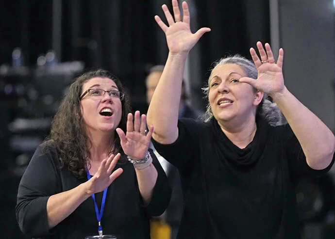 Two women in dark clothes expressively use sign language